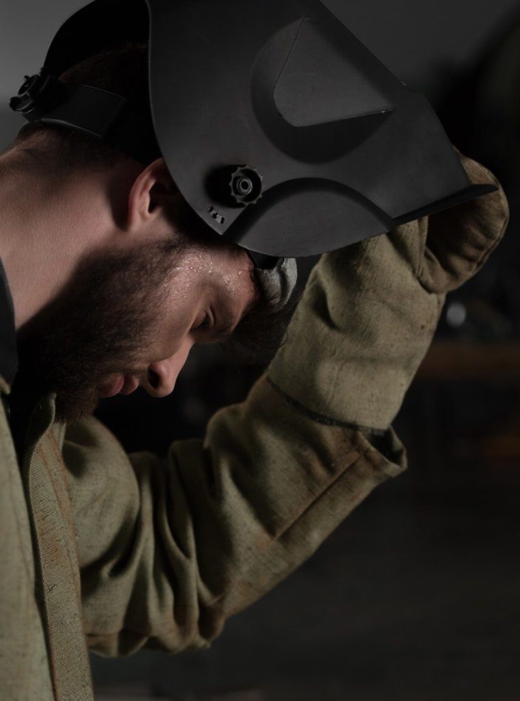 side-view-of-welder-lifting-up-protective-mask-to-look-at-his-work.jpg